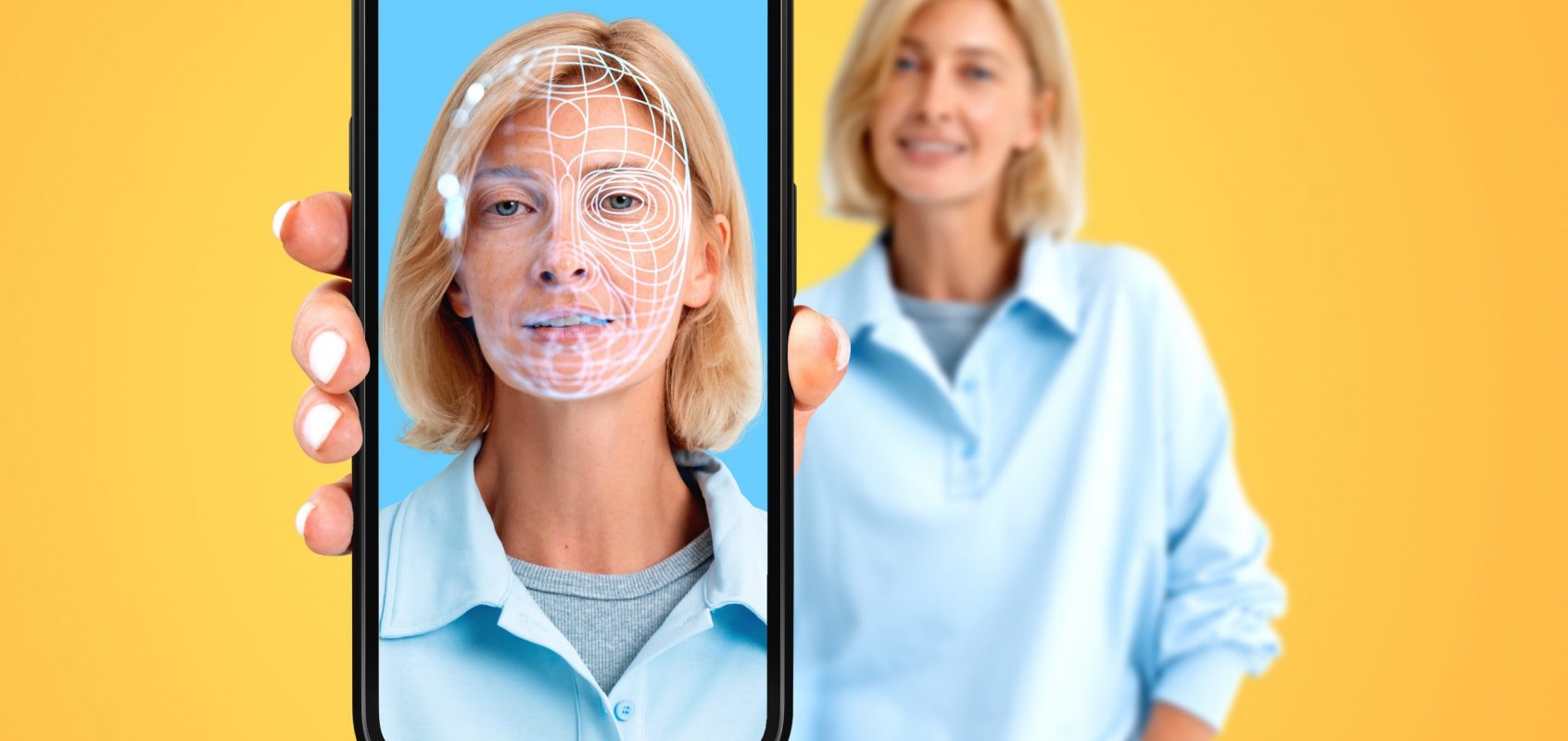 Lächelnde Frau zeigt Telefon mit lächelndem Gesicht und biometrischem Scannen, orangefarbener Hintergrund. Konzept der Gesichtstausch, Nachahmung, soziale Medien und Überprüfung